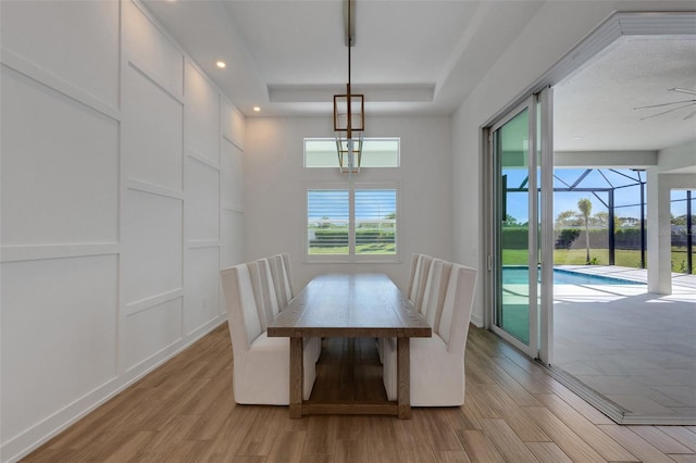 dining space with a raised ceiling, recessed lighting, and light wood-style floors