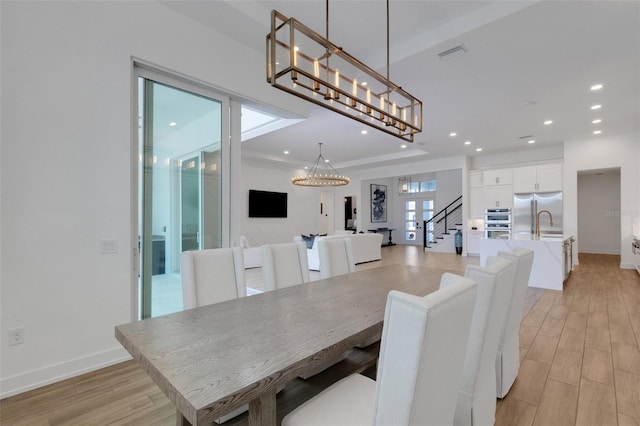 dining space featuring stairway, a notable chandelier, light wood-style floors, and recessed lighting