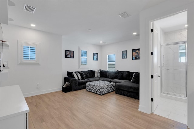 living area with light wood-type flooring, visible vents, and plenty of natural light