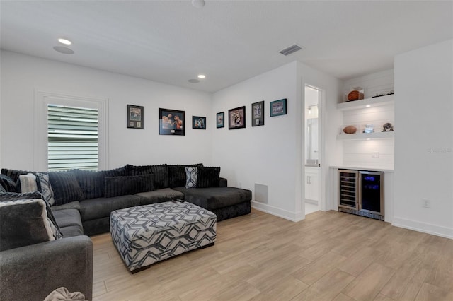 living room featuring a dry bar, light wood-style flooring, visible vents, and baseboards