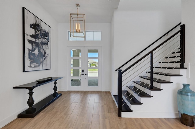 entrance foyer featuring french doors, stairs, baseboards, and wood finished floors