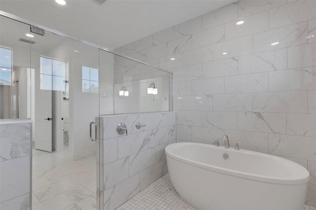 bathroom with a shower stall, tile walls, marble finish floor, and a freestanding tub