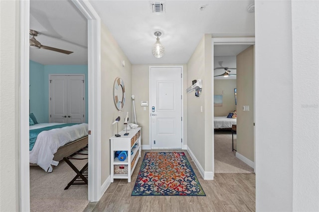 foyer entrance featuring light wood finished floors, visible vents, baseboards, and ceiling fan