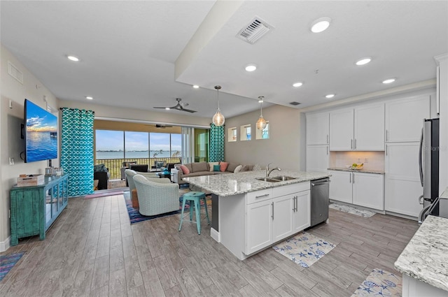 kitchen featuring visible vents, a sink, open floor plan, appliances with stainless steel finishes, and a kitchen island with sink