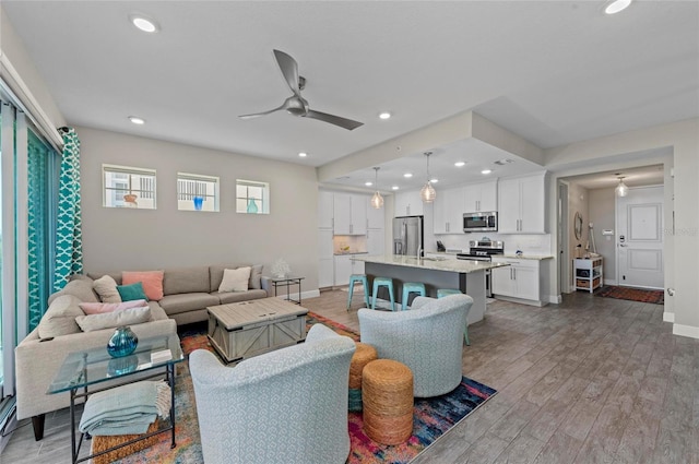 living room featuring recessed lighting, light wood-type flooring, baseboards, and ceiling fan