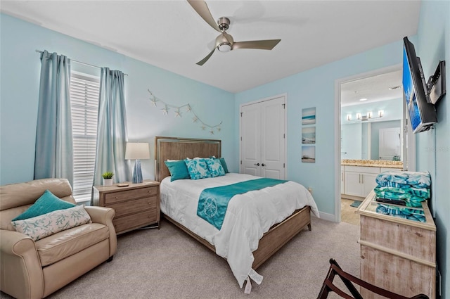 bedroom featuring a ceiling fan, baseboards, a closet, ensuite bathroom, and light colored carpet