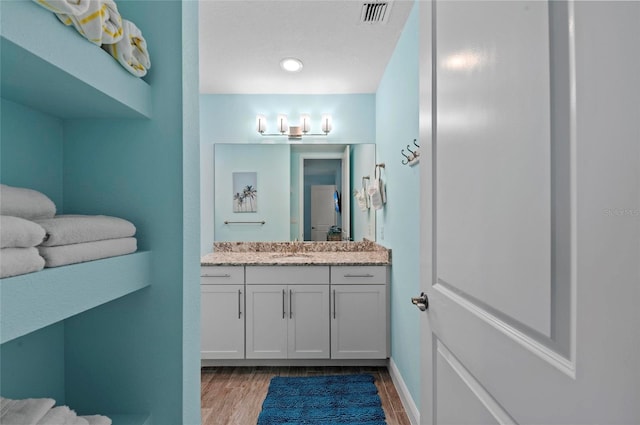 bathroom featuring visible vents, vanity, baseboards, and wood finished floors