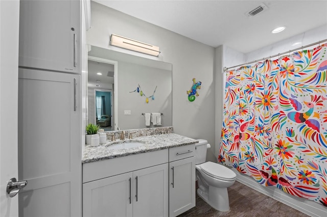 bathroom featuring visible vents, toilet, a shower with curtain, wood finished floors, and vanity