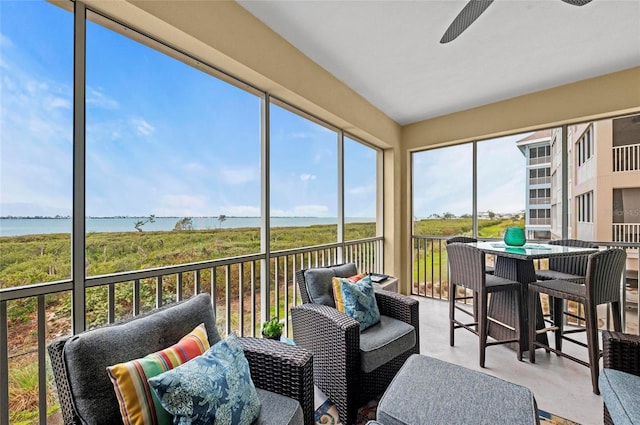 sunroom / solarium featuring ceiling fan and a water view