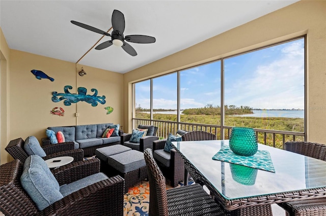 sunroom with ceiling fan and a water view