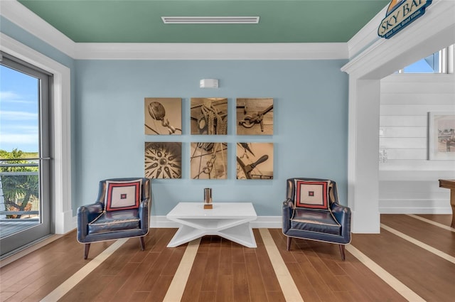 sitting room with visible vents, baseboards, wood finished floors, and crown molding