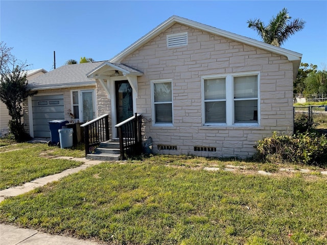 view of front facade with a front yard, an attached garage, stone siding, and crawl space