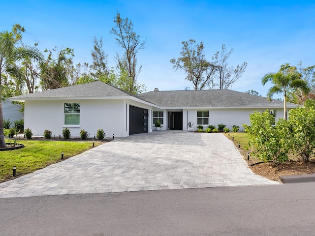 ranch-style home with stucco siding, an attached garage, decorative driveway, and a front lawn