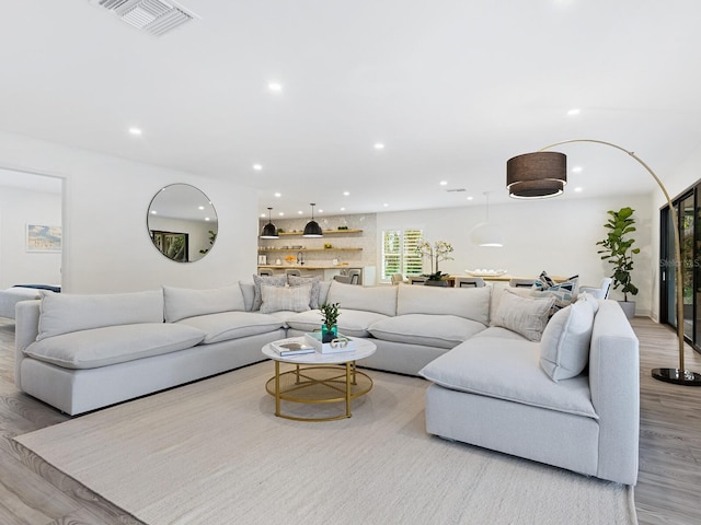 living area with recessed lighting, visible vents, and light wood finished floors