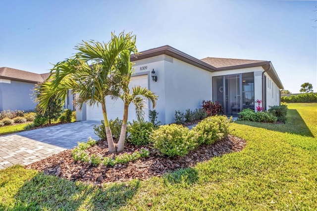 view of side of home with a yard, stucco siding, decorative driveway, and a garage