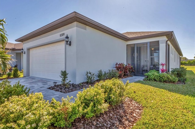 view of front facade with a front yard, an attached garage, driveway, and stucco siding