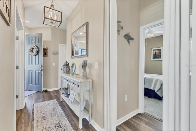 foyer featuring dark wood finished floors, a notable chandelier, and baseboards