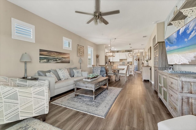 living room with dark wood-style flooring and ceiling fan with notable chandelier