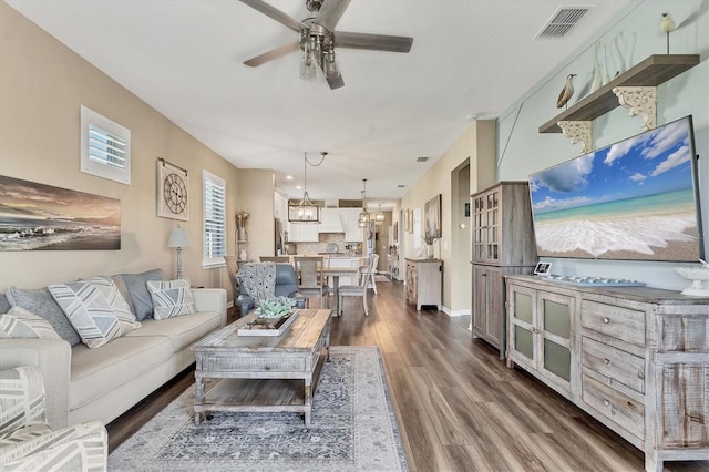 living room with visible vents, baseboards, dark wood-type flooring, and a ceiling fan