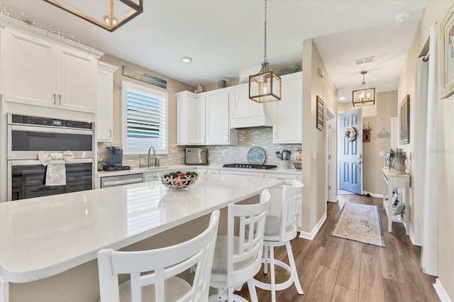 kitchen with visible vents, stainless steel appliances, decorative backsplash, light countertops, and white cabinetry