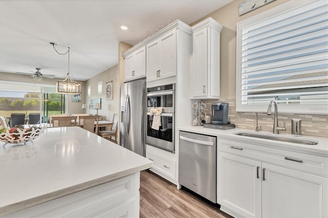 kitchen featuring tasteful backsplash, appliances with stainless steel finishes, light countertops, and a sink