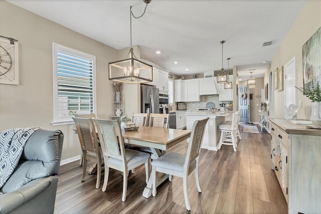 dining room featuring an inviting chandelier, wood finished floors, visible vents, and baseboards