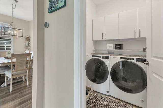 washroom with washer and clothes dryer, a notable chandelier, cabinet space, and wood finished floors