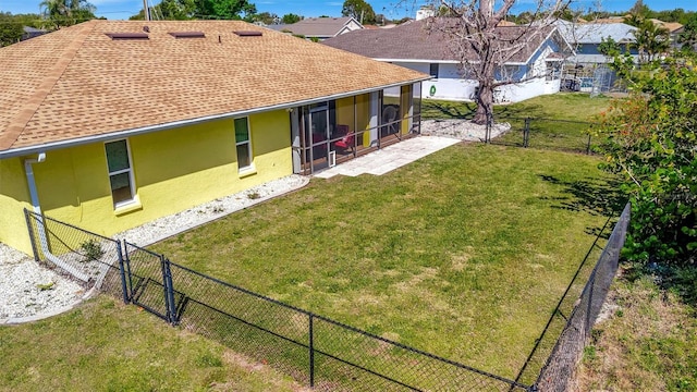 rear view of property featuring a sunroom, stucco siding, a yard, a fenced backyard, and a gate