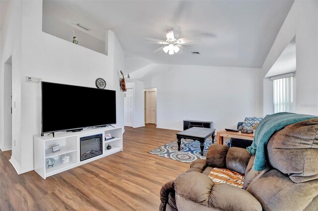 living area featuring wood finished floors, a ceiling fan, visible vents, baseboards, and lofted ceiling