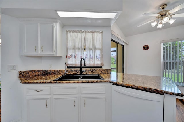 kitchen featuring white cabinetry, a peninsula, a skylight, a sink, and dishwasher