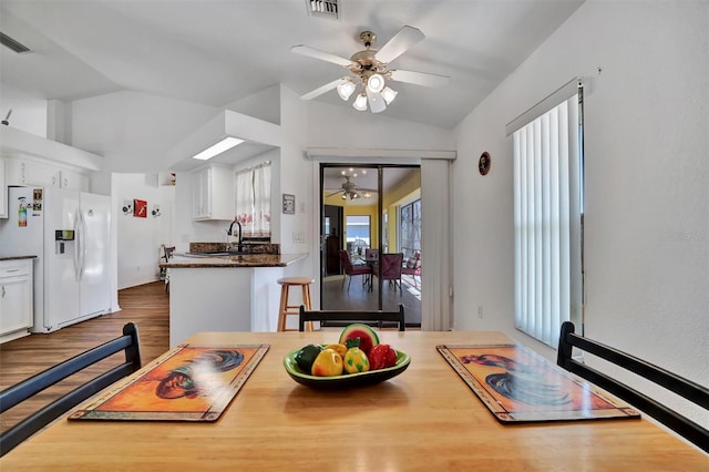 dining space with visible vents, wood finished floors, ceiling fan, and vaulted ceiling