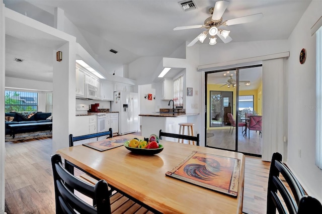 dining room featuring visible vents, vaulted ceiling, a ceiling fan, and light wood finished floors