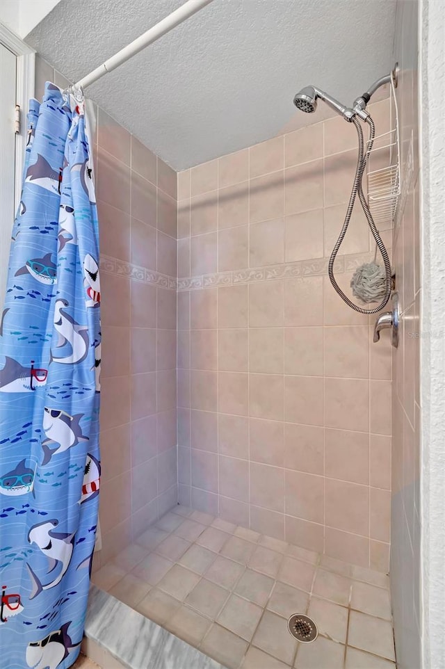 bathroom with a tile shower and a textured ceiling