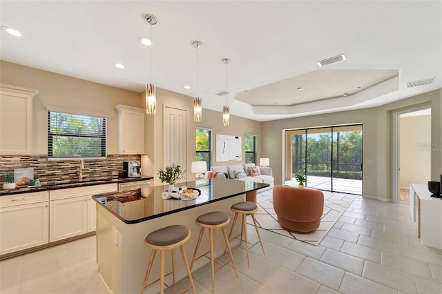 324 Casalino Dr, Nokomis, FL 34275 - kitchen featuring visible vents, a tray ceiling, dark countertops, backsplash, and open floor plan
