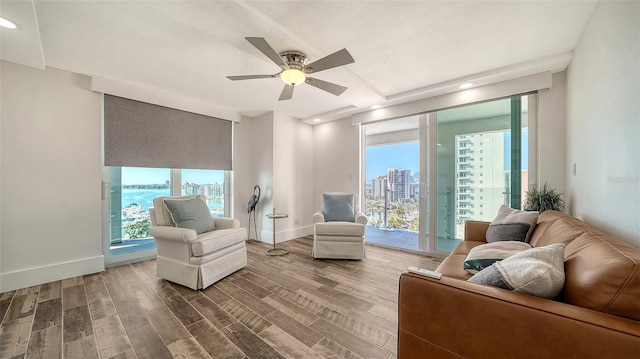 sitting room with baseboards, a view of city, plenty of natural light, and wood finished floors