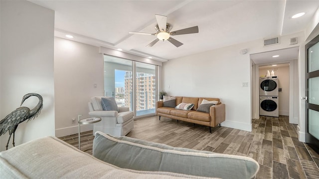 living area with visible vents, stacked washer and clothes dryer, ceiling fan, and wood tiled floor