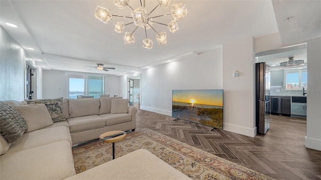 living room with recessed lighting, a healthy amount of sunlight, ceiling fan with notable chandelier, and baseboards