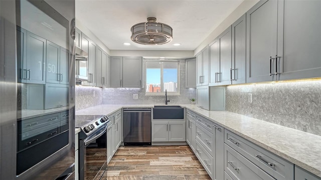 kitchen featuring a sink, light wood-style floors, range with electric stovetop, dishwasher, and backsplash