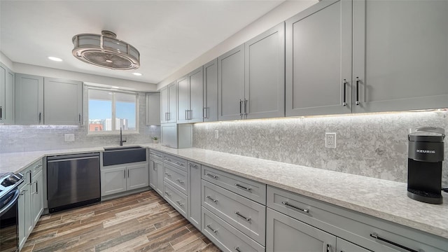 kitchen featuring gray cabinets, a sink, stainless steel appliances, light wood-type flooring, and backsplash