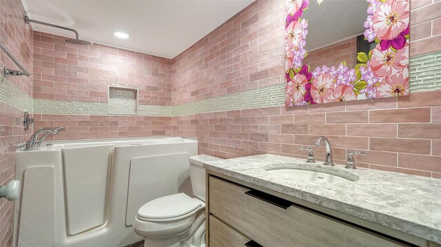 full bath featuring vanity, a tub to relax in, recessed lighting, tile walls, and toilet