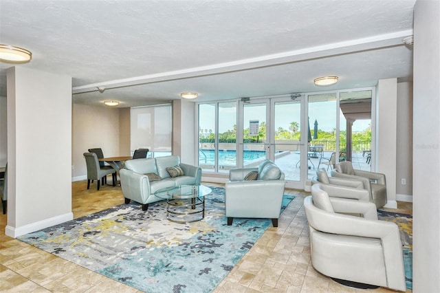 living room with a textured ceiling, baseboards, and stone finish flooring