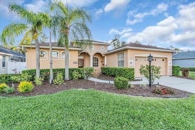 view of front facade with stucco siding, driveway, a front yard, and a garage