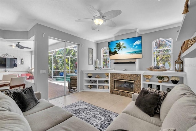 tiled living area with ceiling fan, a fireplace, and ornamental molding