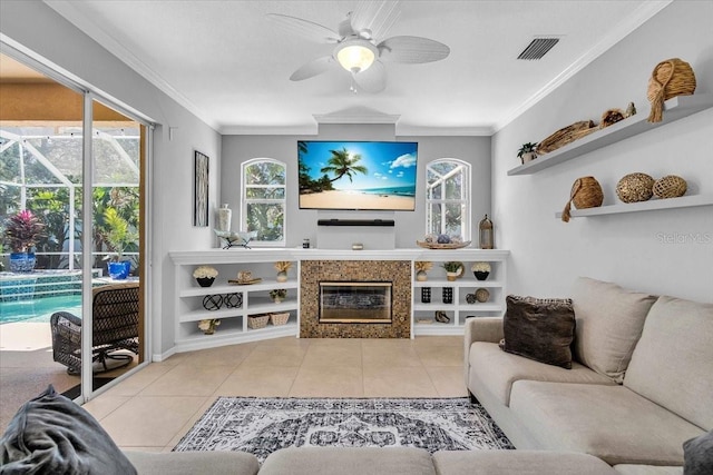 tiled living room with visible vents, a fireplace, ceiling fan, and ornamental molding