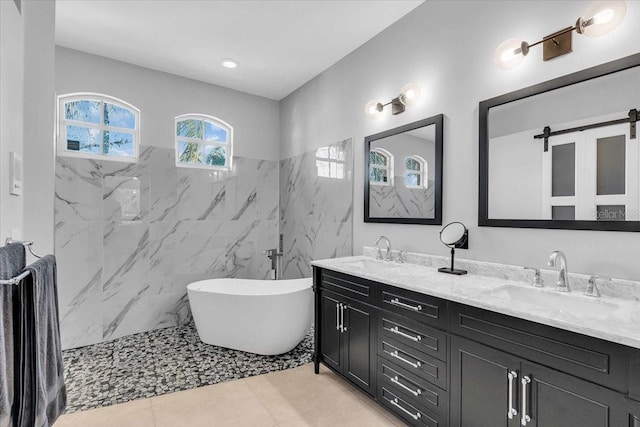 full bath featuring a freestanding bath, double vanity, tile patterned flooring, and a sink