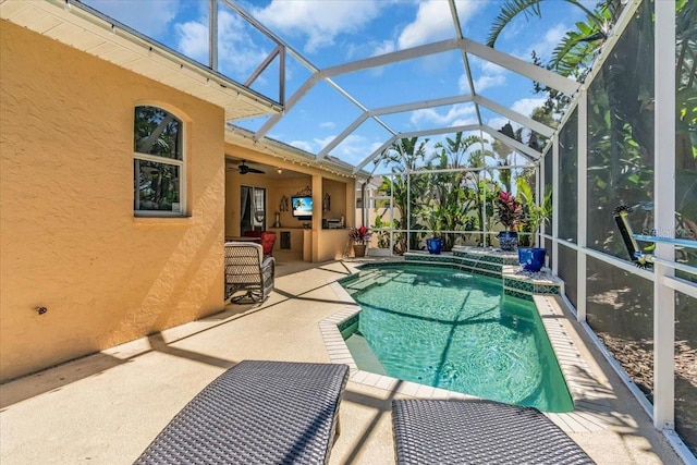 outdoor pool featuring glass enclosure, a patio, and ceiling fan