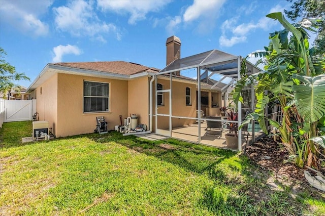 rear view of house with stucco siding, a patio, a yard, and fence