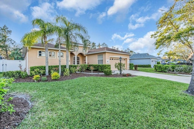 mediterranean / spanish-style home featuring stucco siding, an attached garage, driveway, and a front yard