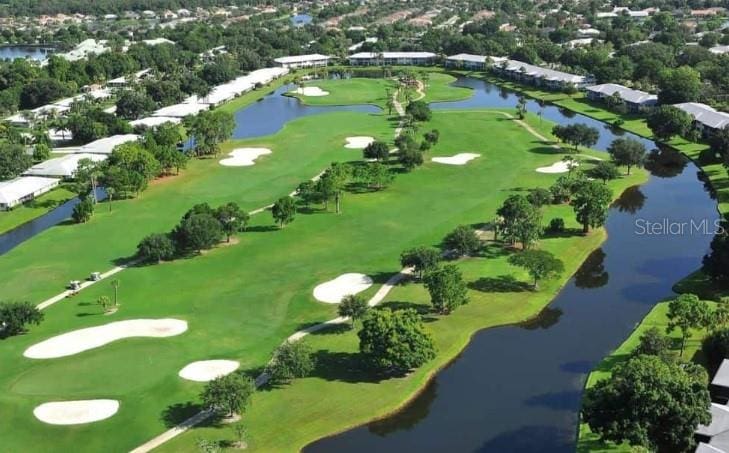 birds eye view of property with golf course view and a water view