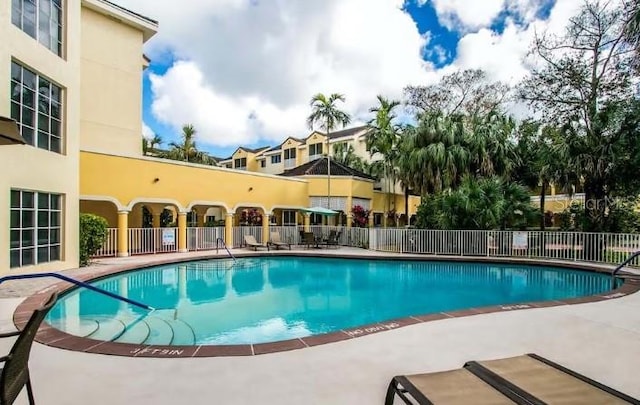 pool with a patio area and fence